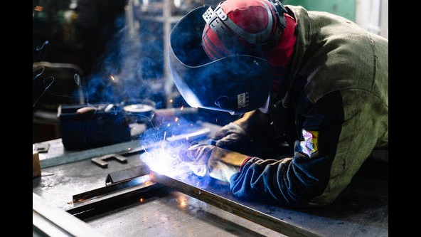 Welder laying a bead on steel plate, arc sparks flying